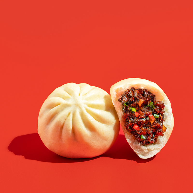 Fluffy bao bun filled with delicious Teriyaki chicken on a red backdrop